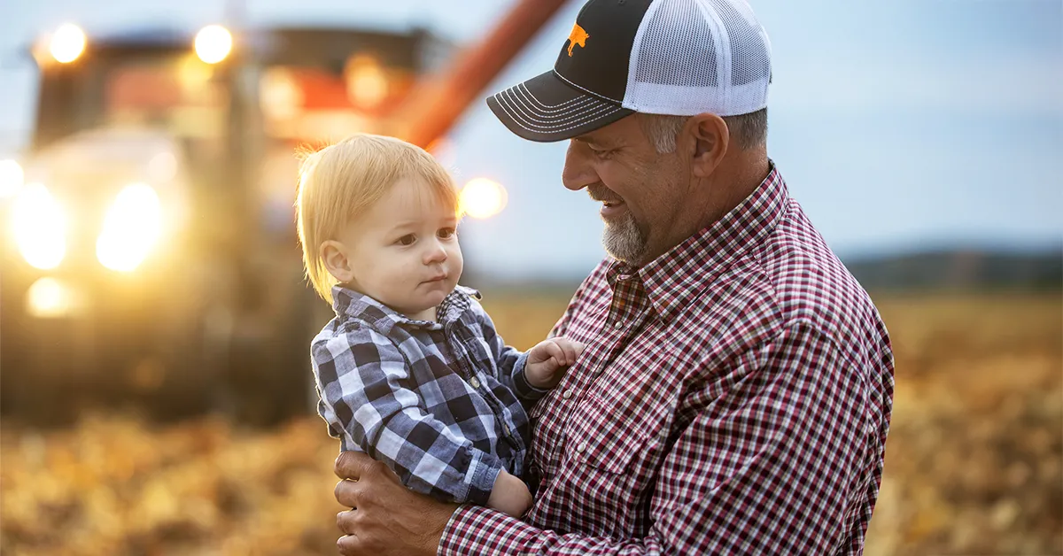 Pork producer holding his grandson.